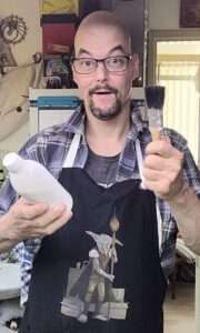 A happy Baldie in his work Goblinsquire apron holding his tools